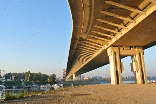 Underside of a long winding yellow modern bridge, on a sunny afternoon. Modern architecture; Belgrade, Serbia.