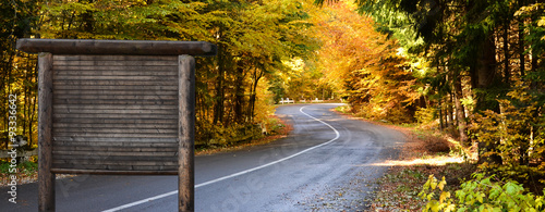 Panoramic view of a road and advertising panel in fall season in natural reservation forest of Tusnad #93336642