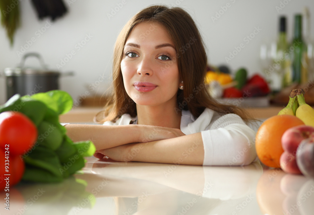 Young woman standing near desk in the kitchen . Young woman standing near desk in the kitchen .