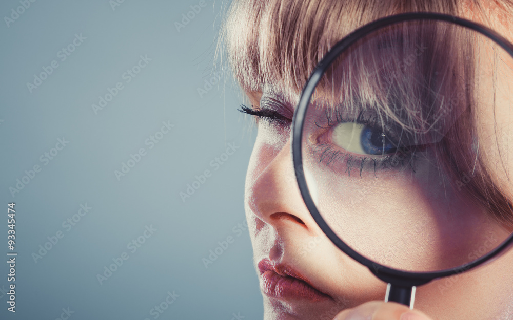 Woman hand holding magnifying glass on eye Woman hand holding magnifying glass on eye