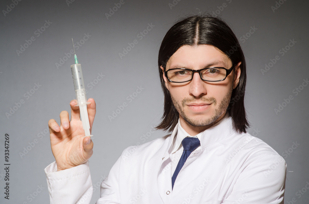 Male doctor holding syringe against gray Male doctor holding syringe against gray