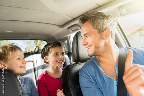 father with beard is talking with his two kids in the car