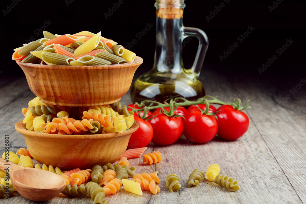 Raw eliche and penne tricolori pasta in the wooden bowls