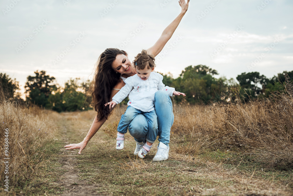 mother and daughter playing on autumn field together, loving family having fun outdoors