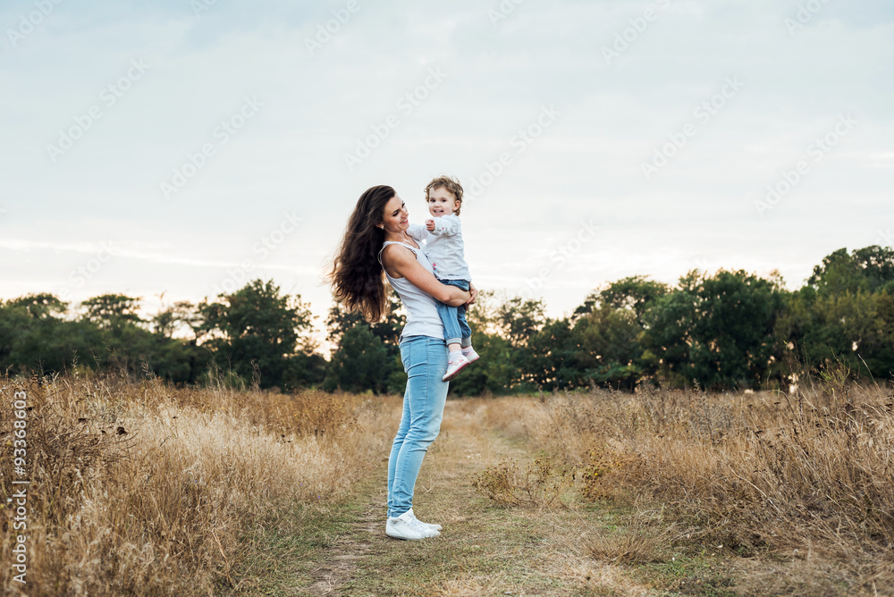 mother and daughter playing on autumn field together, loving family having fun outdoors