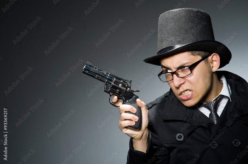 Criminal in black coat holding hadgun against gray Criminal in black coat holding hadgun against gray