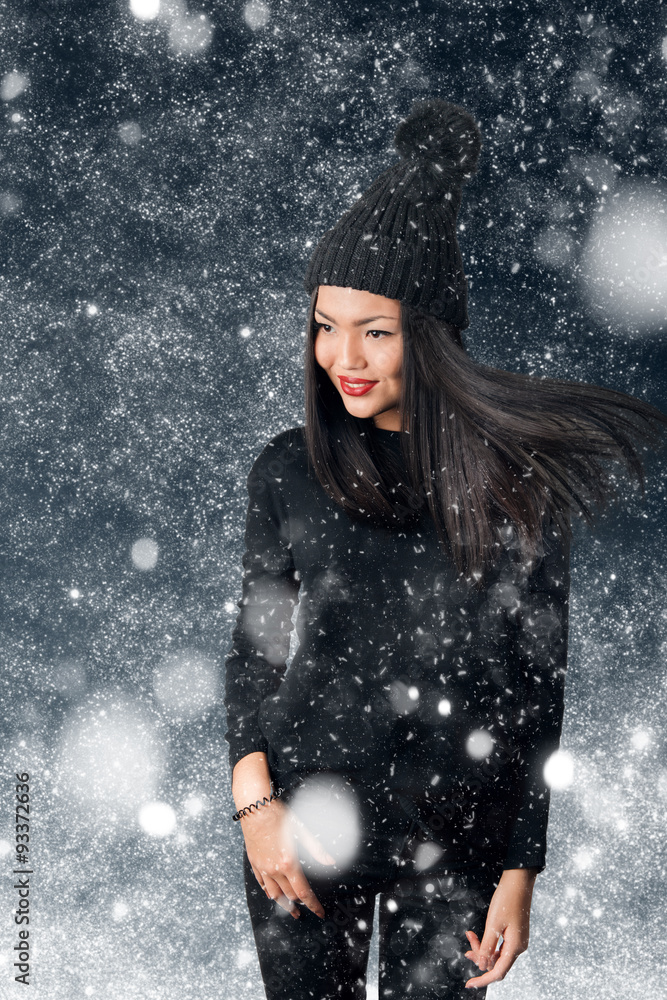 Beautiful asian woman wearing knitted hat with pompom in a snow.