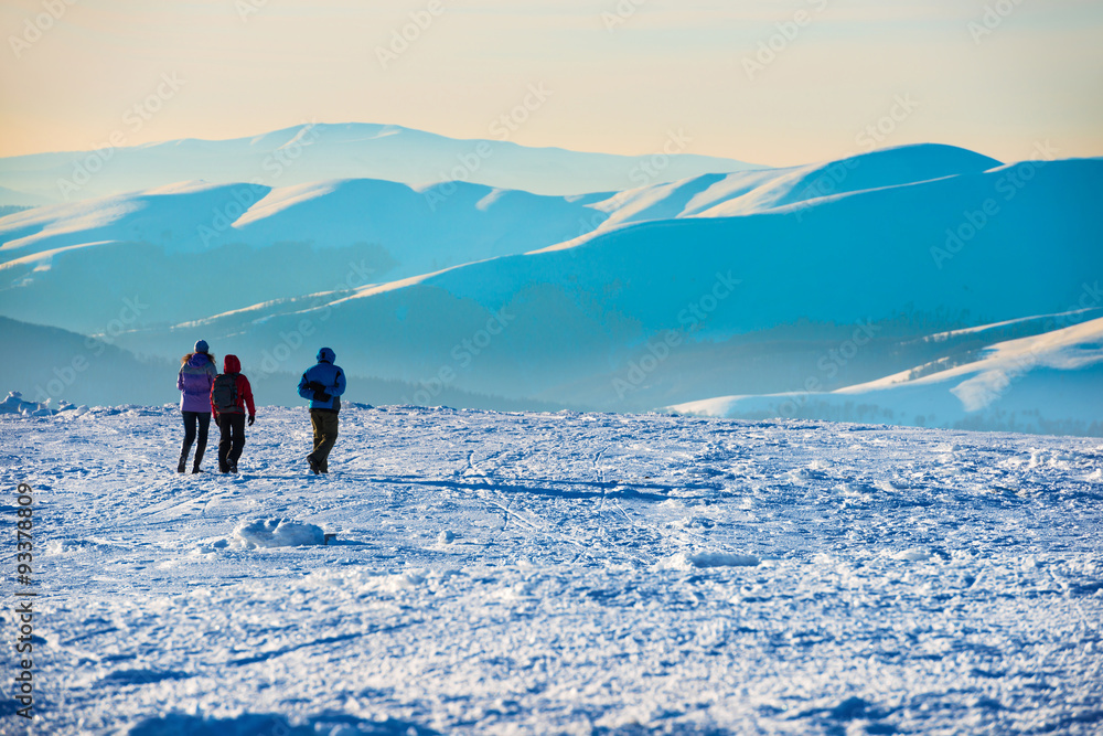 People walking at sunset in winter mountains