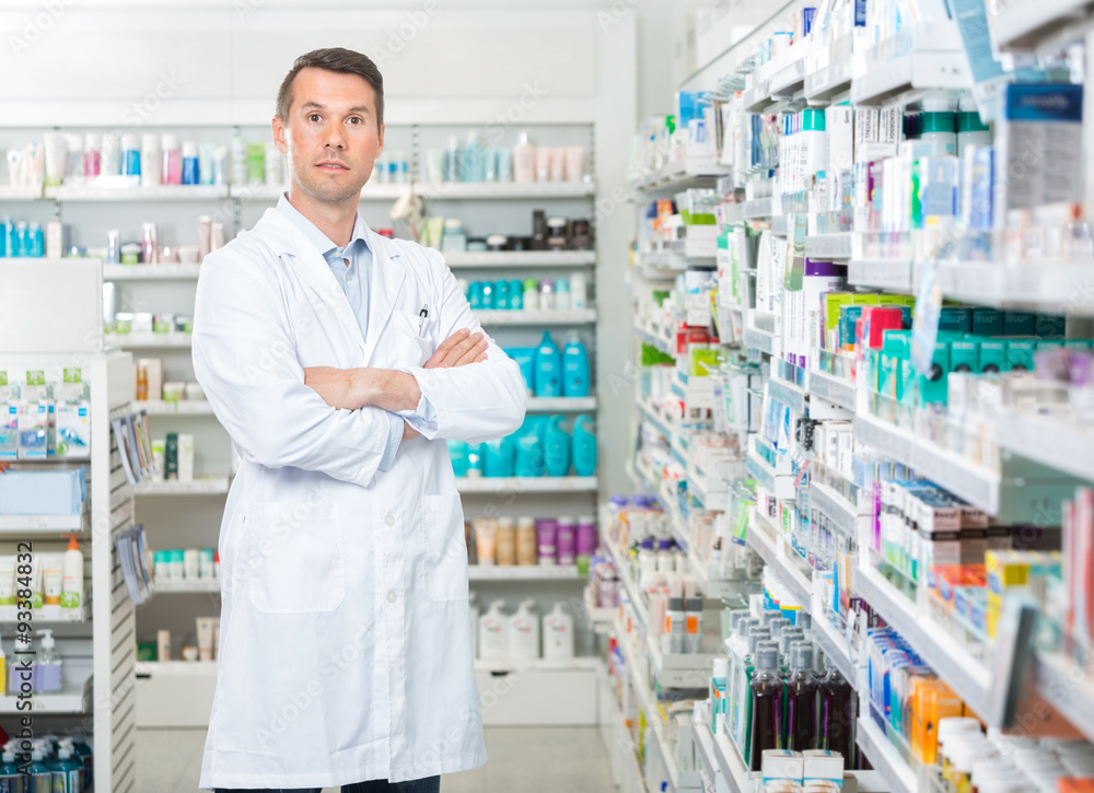 Confident Pharmacist Standing Arms Crossed In Pharmacy