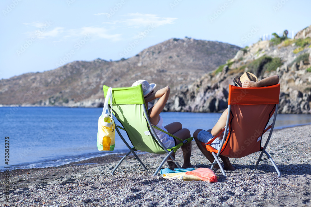 Young couple is sitting on chaise lounge at the beach Young couple is sitting on chaise lounge at the beach