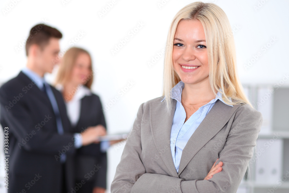 Pretty businesswoman in office with colleagues in the background Pretty businesswoman in office with colleagues in the background