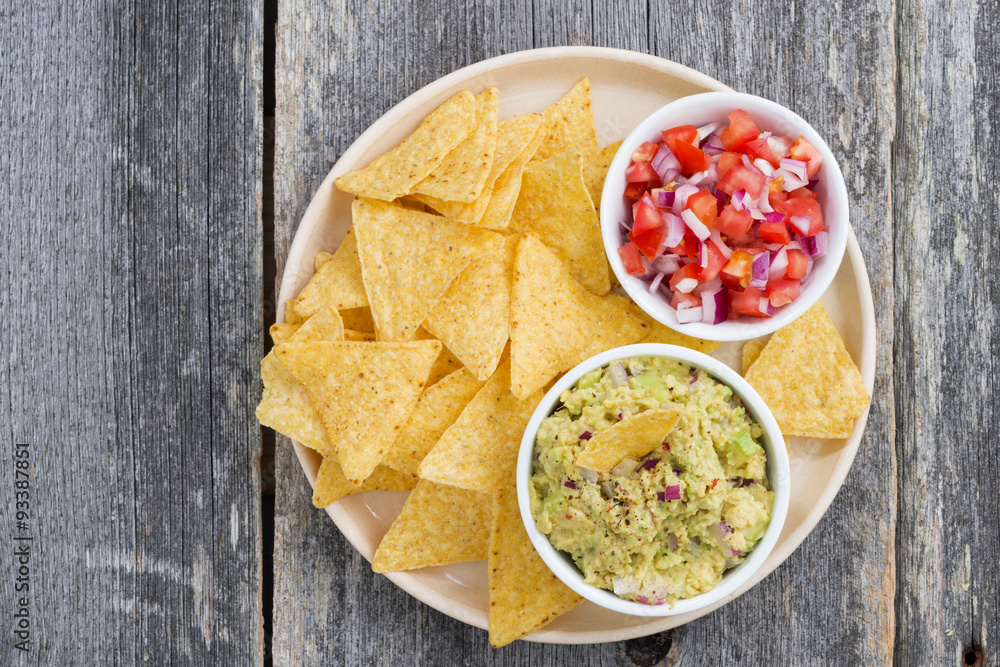 guacamole, tomato salsa and corn chips on a plate, top view guacamole, tomato salsa and corn chips on a plate, top view