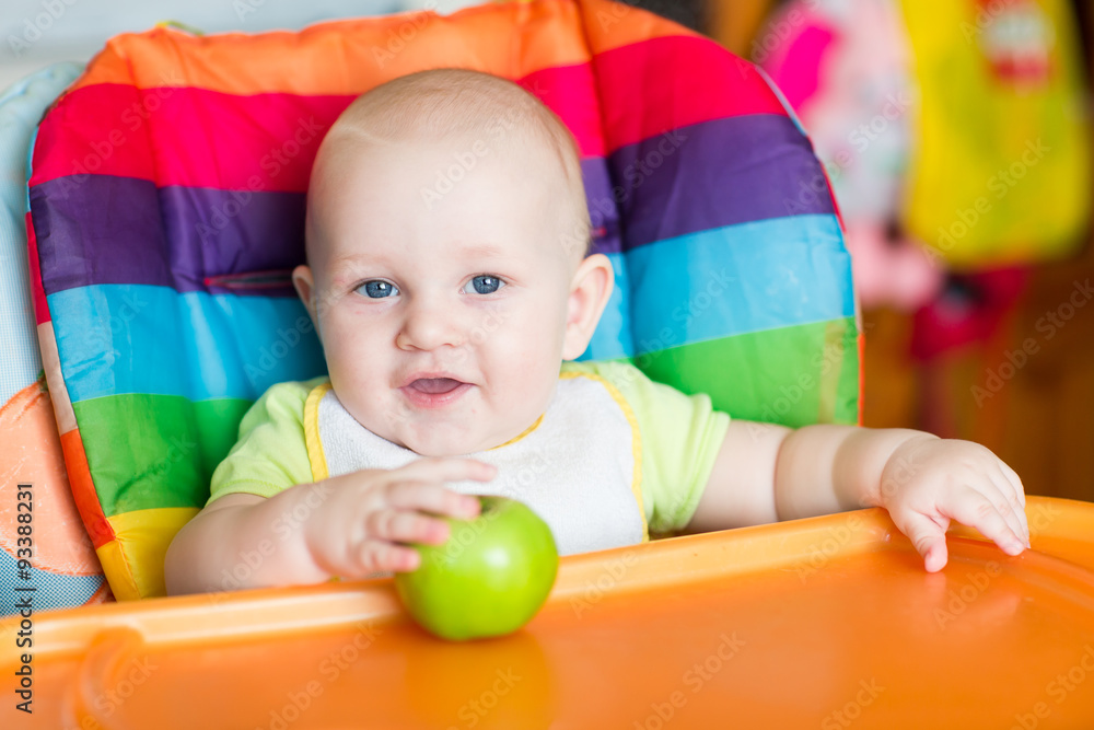 Obraz premium Adorable baby eating apple in high chair
