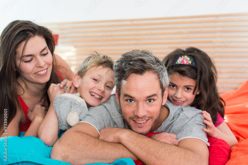 Smiling parents having fun in bed with their two children. Smiling parents having fun in bed with their two children.