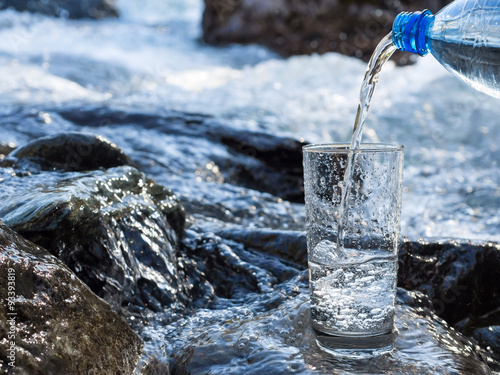 Foto Water pouring into a glass from bottle