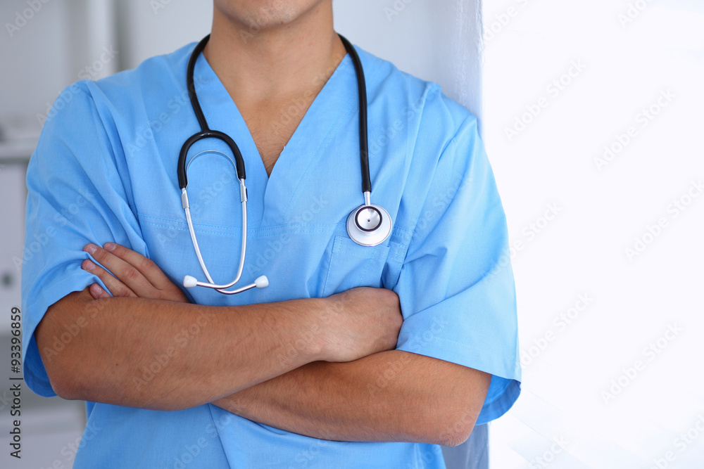 Portrait of unknown male surgeon doctor standing near the wall in hospital office, stethoscope Portrait of unknown male surgeon doctor standing near the wall in hospital office, stethoscope