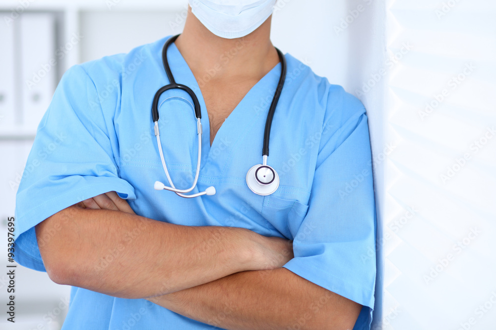 Portrait of unknown male surgeon doctor standing near the wall in hospital office, stethoscope Portrait of unknown male surgeon doctor standing near the wall in hospital office, stethoscope