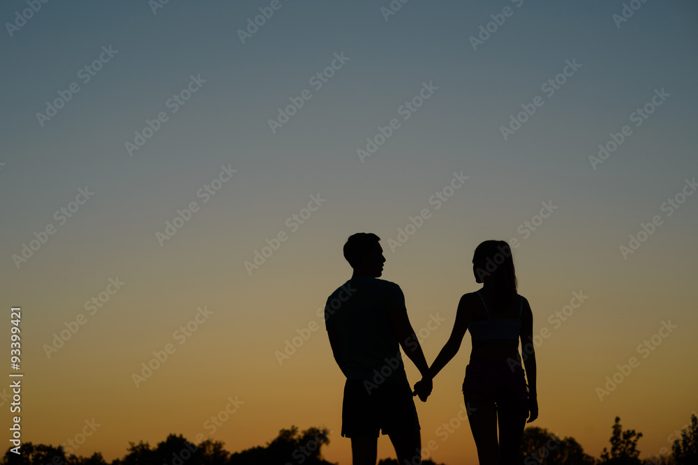 In love couple walking on sunset background.