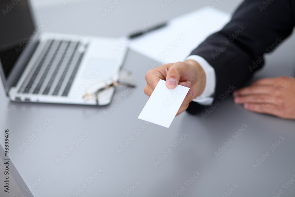 Close-up of businessman giving a business card, sitting at the table Close-up of businessman giving a business card, sitting at the table