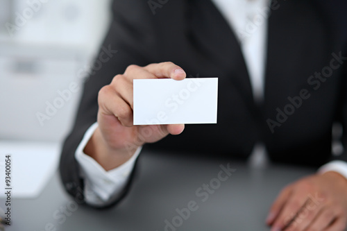 Close-up of businessman giving a business card, sitting at the table