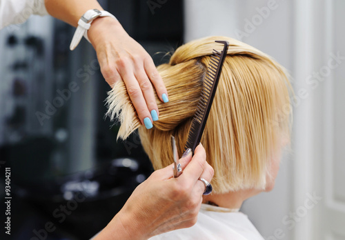 Hairdresser cutting blonde hair