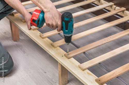 Wooden furniture assembling- woodworker screwing screws using a
