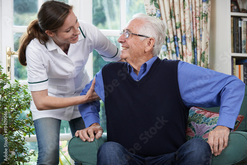 Care Worker Helping Senior Man To Get Up Out Of Chair photo