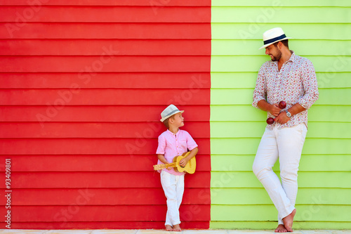 Photography happy father and son with musical instruments near the colorful wall