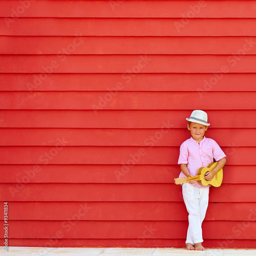 Photography cute kid with ukulele play music near the colorful wall