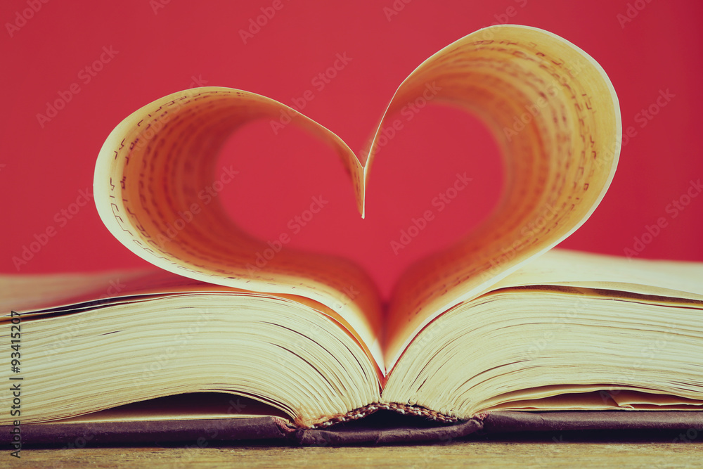 Book pages curved into heart shape on red background Book pages curved into heart shape on red background