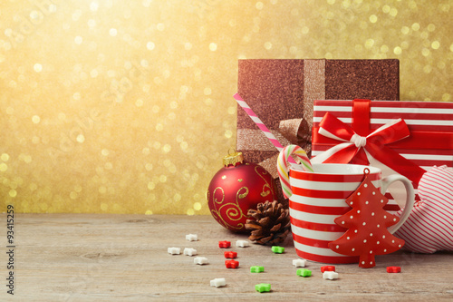 Christmas ornamnets and cup with gift boxes over gold bokeh background photo