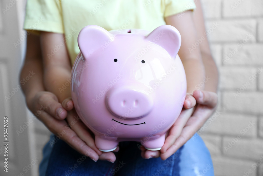 Little girl with her mum and pig moneybox closeup Little girl with her mum and pig moneybox closeup