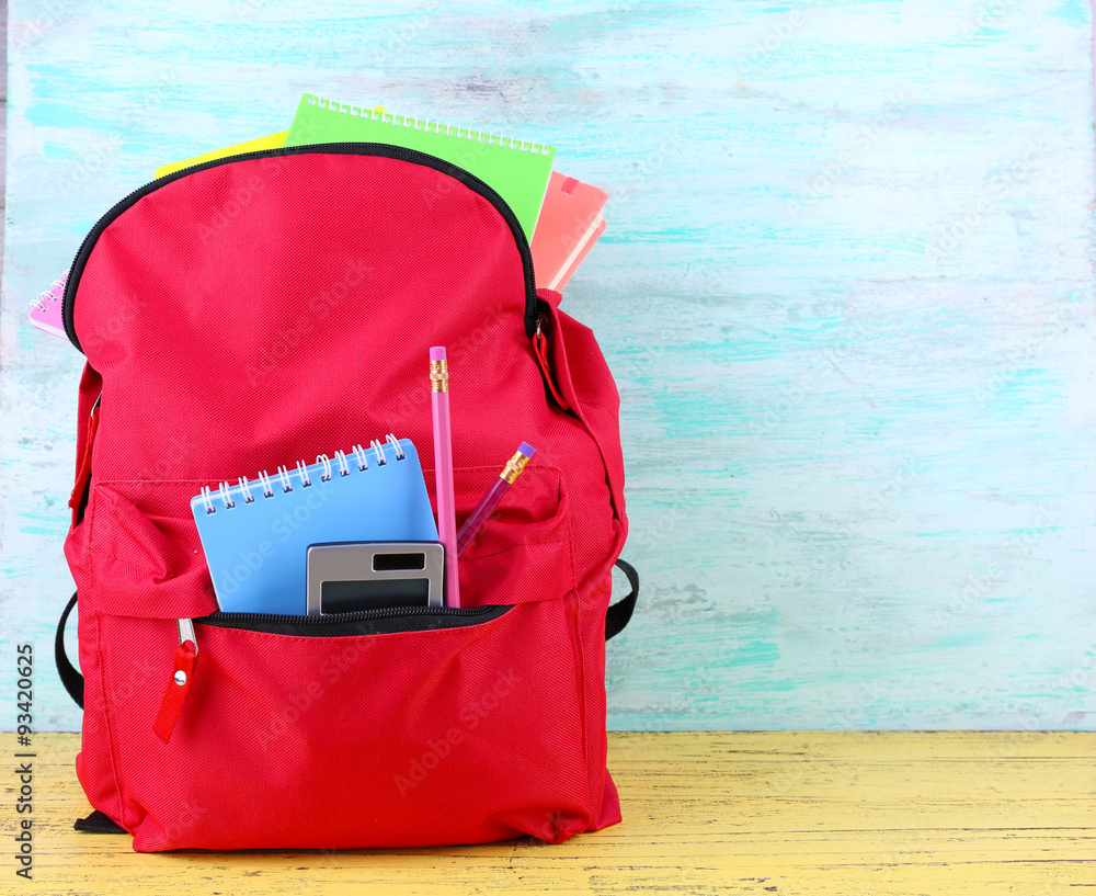 Naklejka premium Red bag with school equipment on wooden background