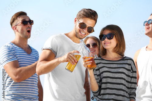 Young people with beer on the riverside