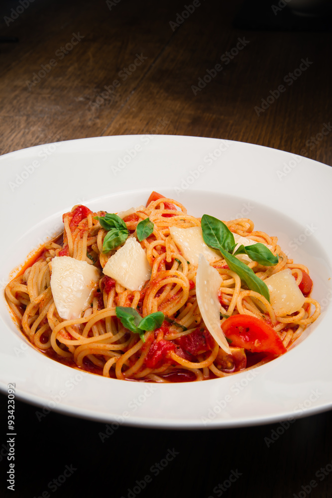 Spaghetti with tomato, parmesan and basil served in a white plate Spaghetti with tomato, parmesan and basil served in a white plate