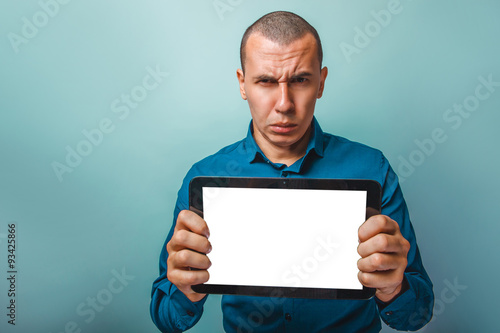a man of European appearance thirty years shows a tablet frowns 