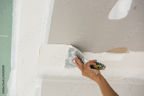man hand with trowel plastering a ceiling, skim coating plaster photo