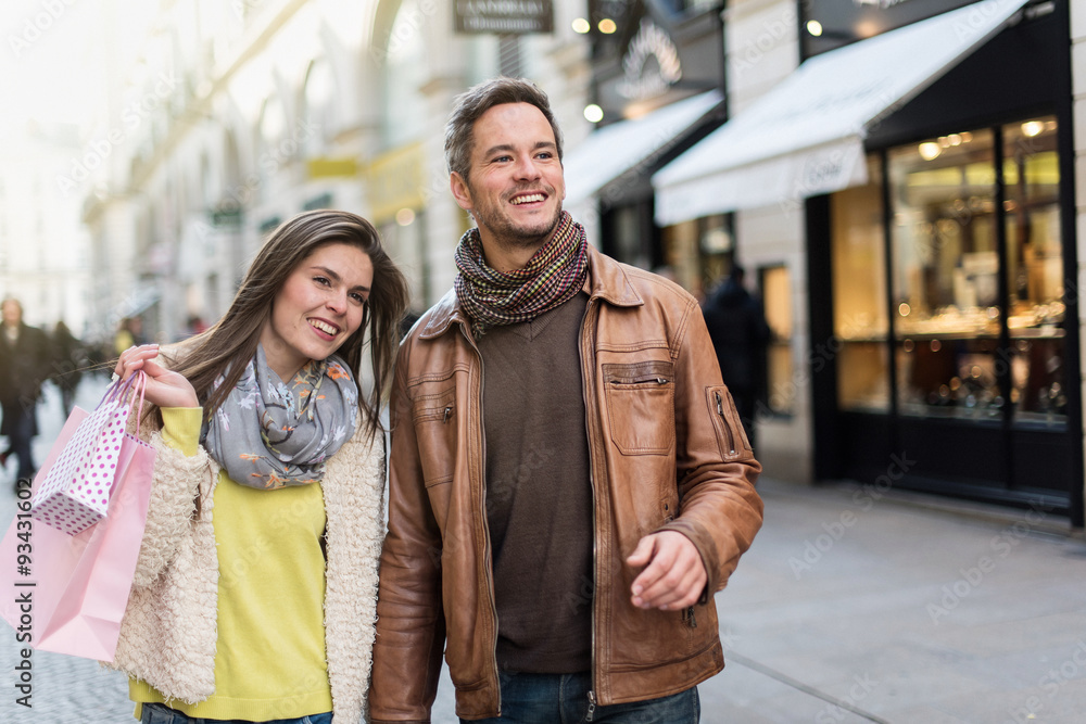 A trendy couple is walking in the city center, shopped