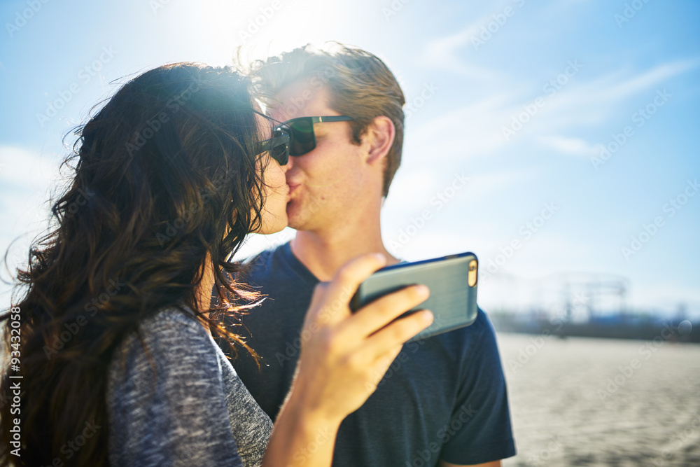couple kissing while taking selfie together