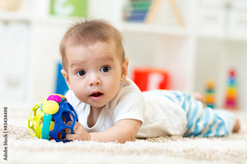 Joyful baby lying on the carpet in nursery room Joyful baby lying on the carpet in nursery room