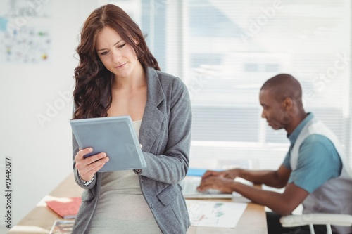 Woman using digital tablet with man working at desk 