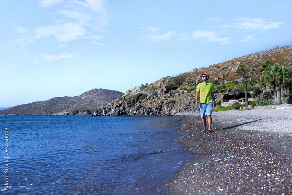Young man is walking along the sea side on a summer day