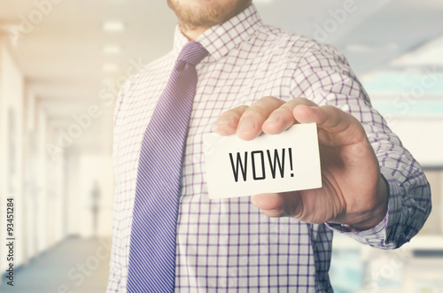 businessman in office showing card with text: WOW