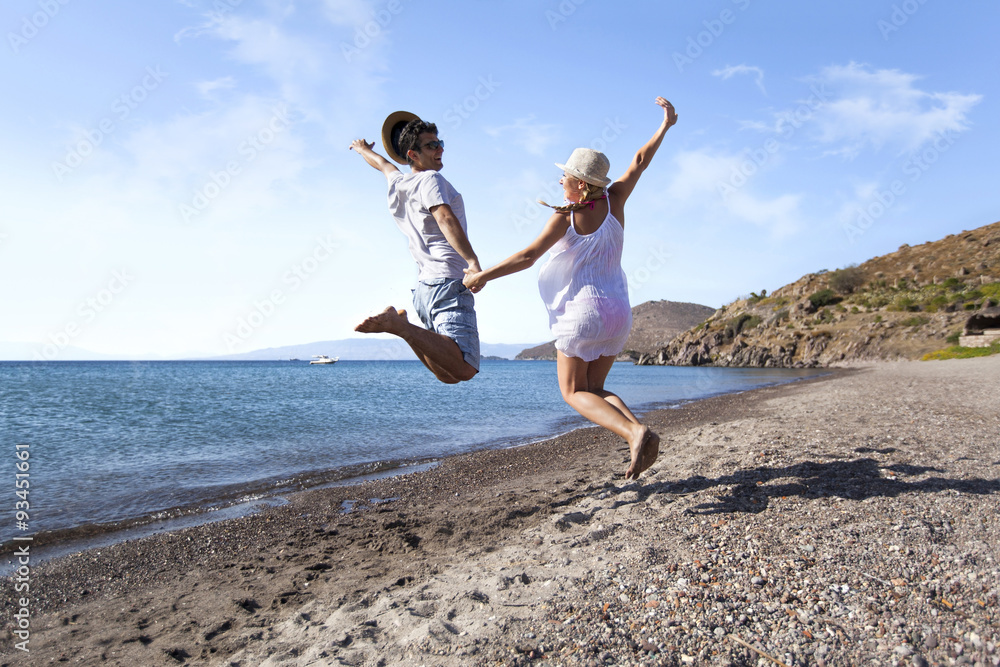 Young couple is jumping on the beach hand to hand Young couple is jumping on the beach hand to hand