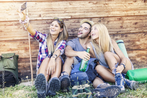 group of smiling friends taking funny selfie with smart phone photo