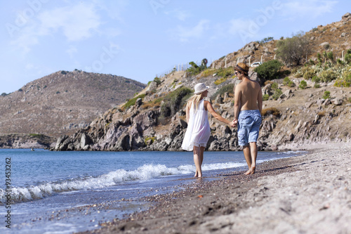 Young couple is walking on the beach hand to hand