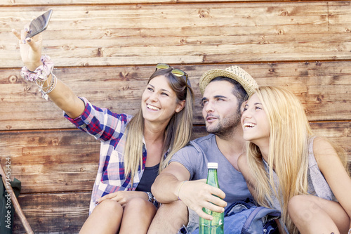 group of smiling friends taking funny selfie with smart phone photo