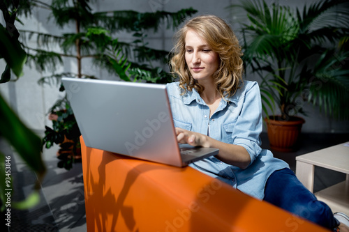 Beautiful young businesswoman using laptop in office with happy