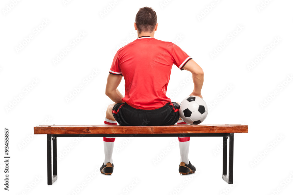 Naklejka premium Football player holding a ball and sitting on a bench
