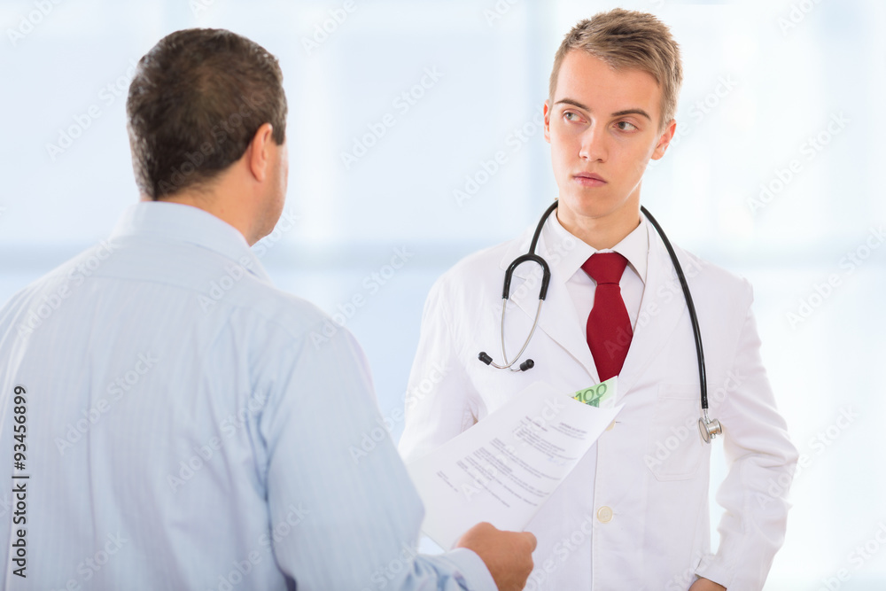 Man offering a corrupt doctor bribe money placed in between documents that need to be falsified Man offering a corrupt doctor bribe money placed in between documents that need to be falsified